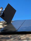 worker installing solar panels on a roof