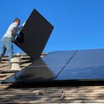 worker installing solar panels on a roof