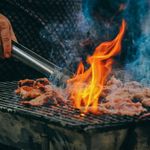 Close-up photo of man cooking meat on a BBQ